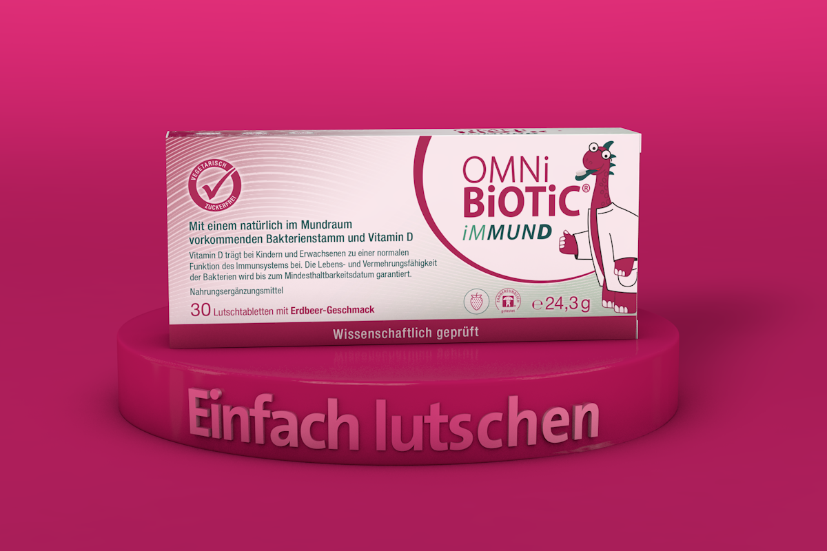 Produktpackung von OMNi-BiOTiC® iMMUND Lutschtabletten auf pinkem Podest mit dem Text „Einfach lutschen“.