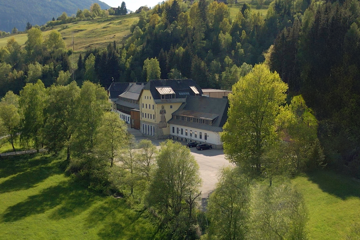 : Luftbildaufnahme vom Firmengebäude der NUTROPIA PHARMA, mehrstöckiges Gebäude umgeben von Bäumen und Wiesen.