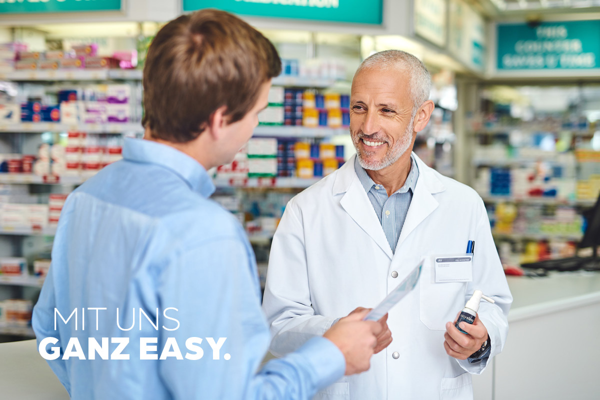 Apotheken-Beratungsgespräch zwischen einem Kunden und einem Apotheker mit dem Slogan ‚Mit uns ganz easy‘.