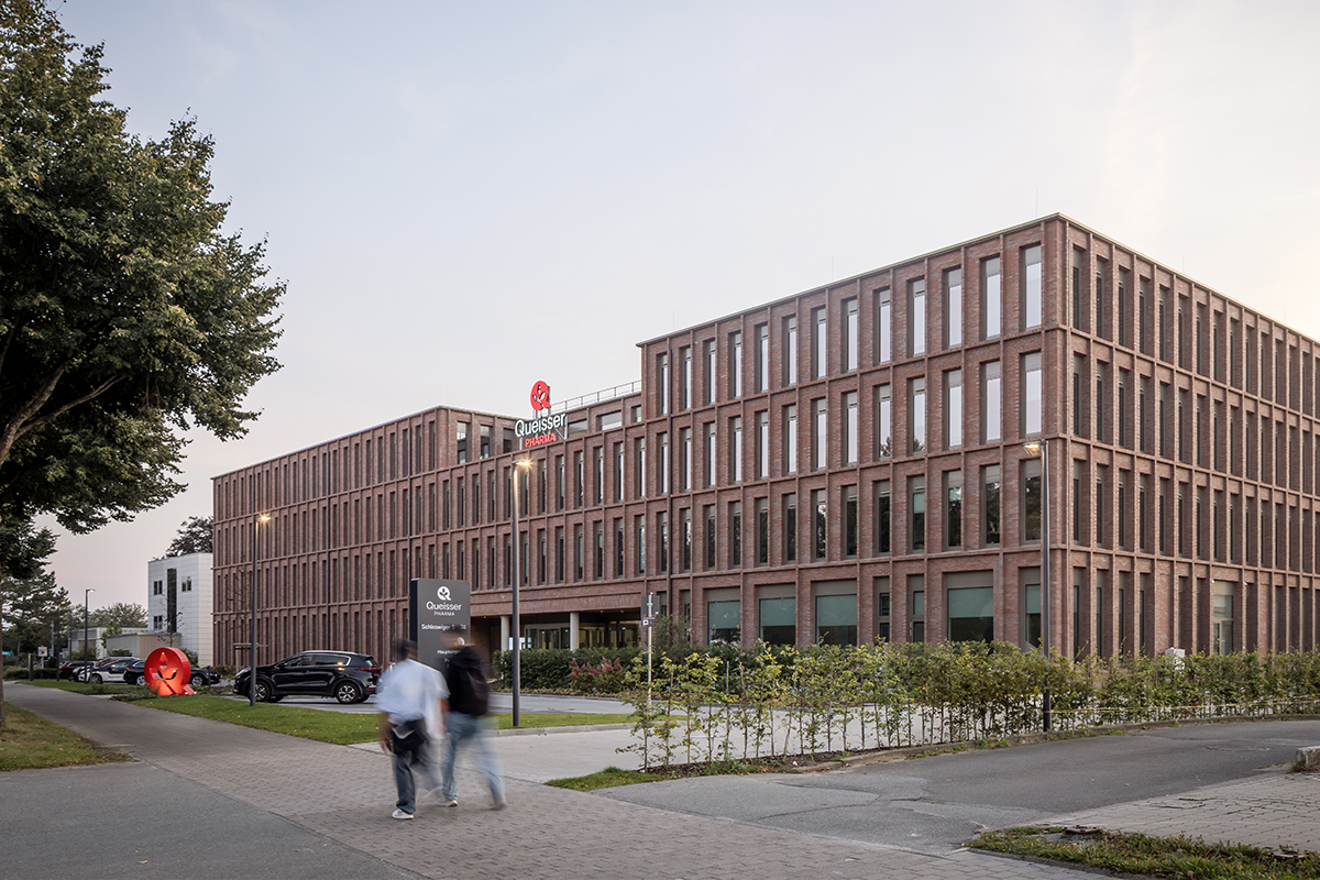 Außenansicht der Firmenzentrale von Queisser Pharma mit Vorplatz und Gehweg