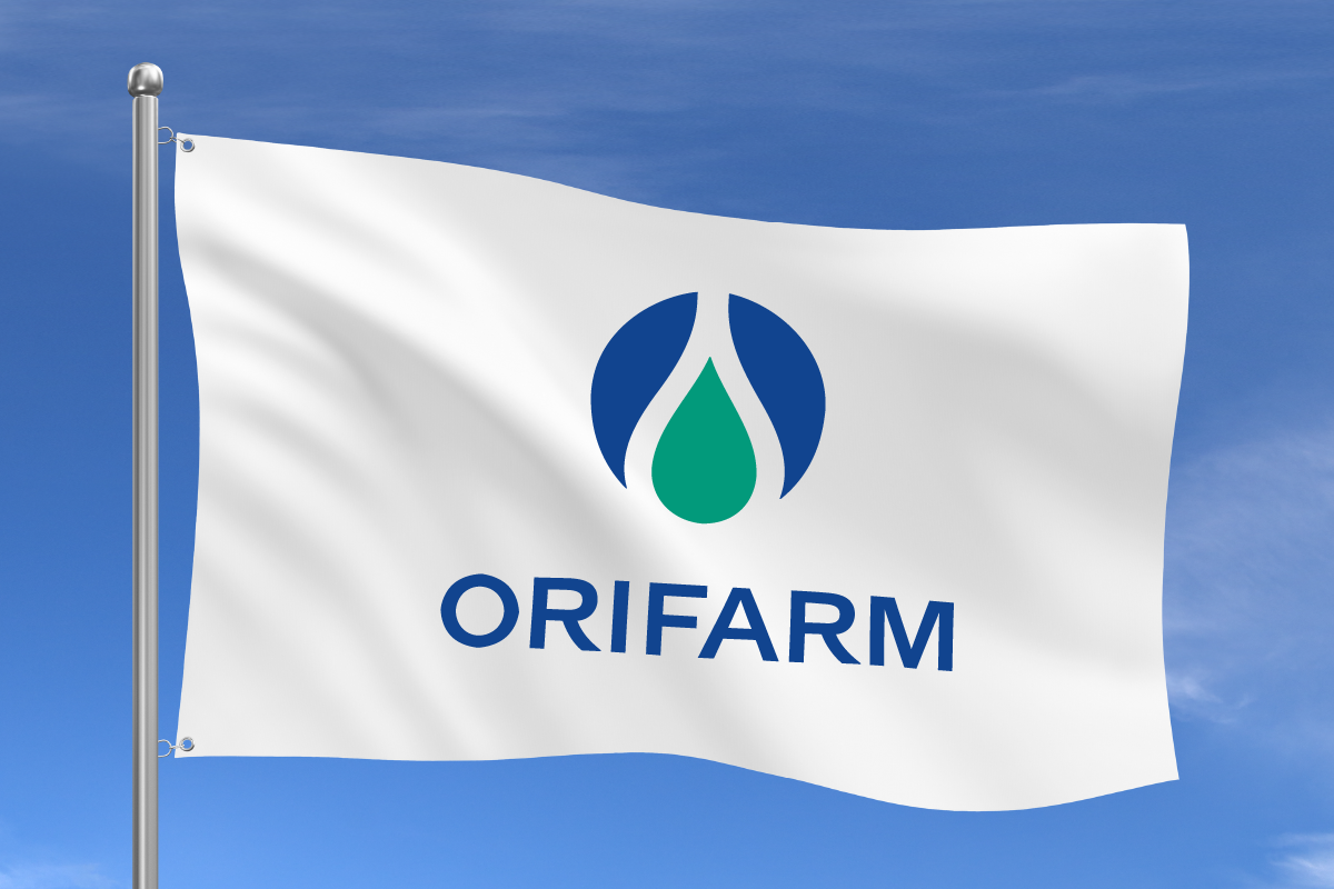 Logo_Flagge Weiße Fahne mit dem Orifarm-Logo: ein blau-grünes Tropfen-Symbol und der Schriftzug ‚ORIFARM‘ in blauen Großbuchstaben, wehend vor blauem Himmel.